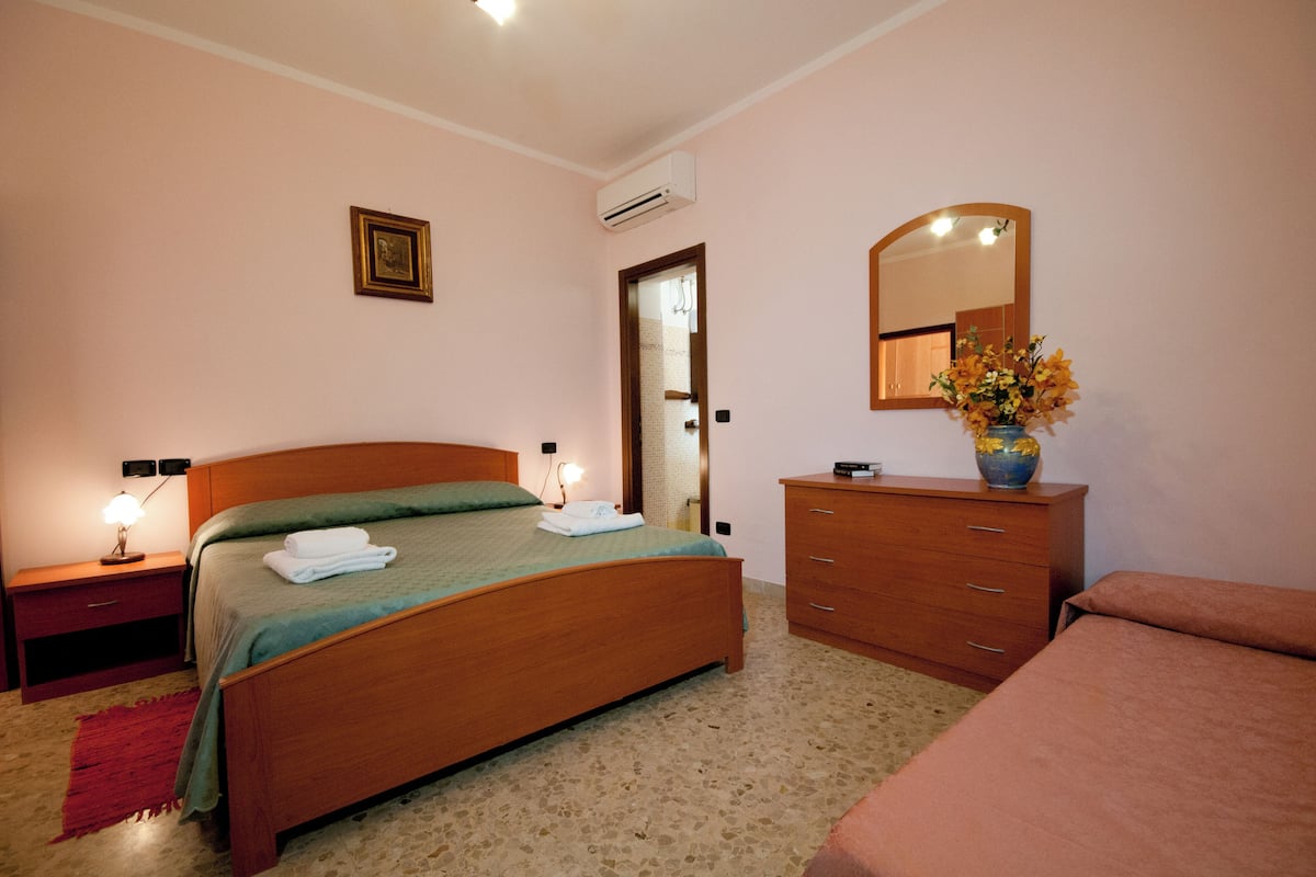 Ein Schlafzimmer mit einem hölzernen Bett, einem Schminktisch, einem Spiegel und einer Tür.