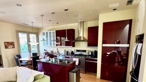 A modern kitchen with stainless steel appliances, a dining area with a table and chairs, and a living room with a sofa and a coffee table. - Alley-By Loft: Smack Dab in the Middle of Ashland!  Steps from Theaters & Lithia (Ashland)