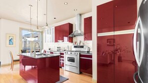 A modern kitchen with red cabinetry, stainless steel appliances, and a central island. - Alley-By Loft: Smack Dab in the Middle of Ashland!  Steps from Theaters & Lithia (Ashland)
