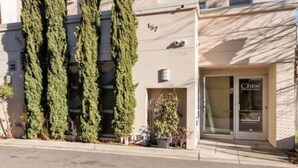 A two-story building with a beige facade, a balcony on the second floor, and a shop entrance with a sign. - Alley-By Loft: Smack Dab in the Middle of Ashland!  Steps from Theaters & Lithia (Ashland)