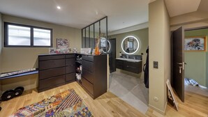 Une chambre à coucher moderne avec un grand lit, une commode, une coiffeuse avec un miroir et un petit espace bureau.