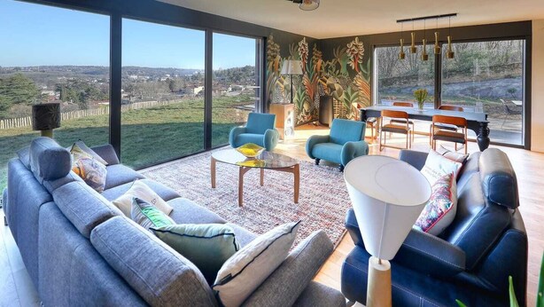 Un salon spacieux avec un grand canapé, une table basse et un coin repas équipé de chaises.