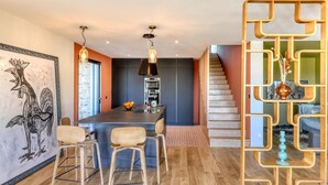 Une cuisine moderne dotée d’un îlot central, de luminaires suspendus et d’un escalier menant à un autre niveau.