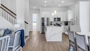 Une cuisine moderne avec des meubles blancs, des appareils en acier inoxydable et un îlot central.