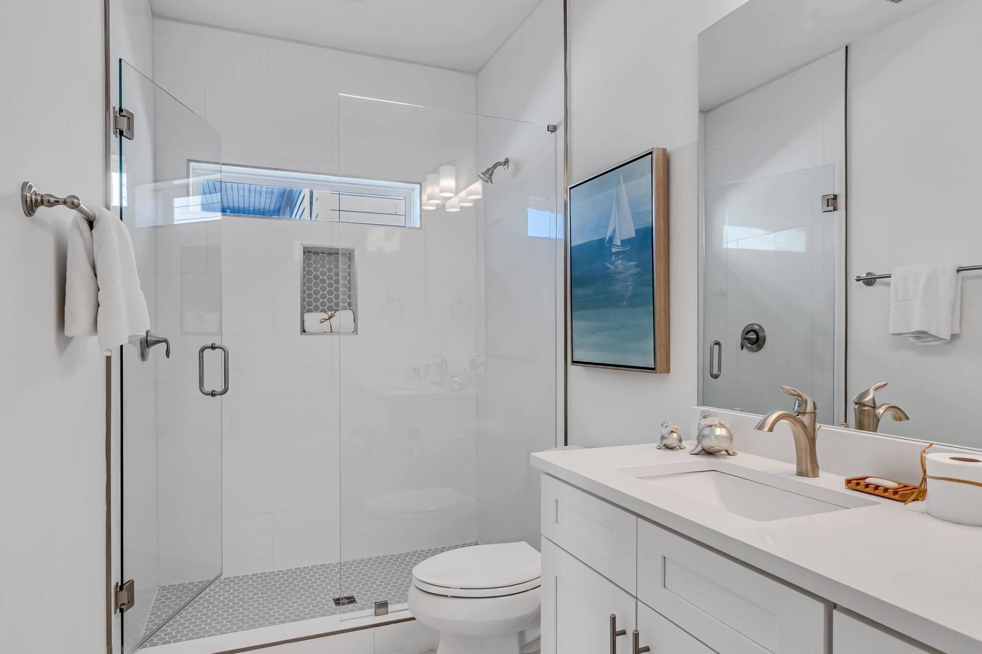 A modern bathroom with a glass shower enclosure, a toilet, and a vanity with a large mirror.