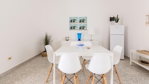 A dining area with a white table, four white chairs, a blue vase, and a small potted plant. - 3702 La Spiaggetta - Padula Fede by Barbarhouse (Porto Cesareo)