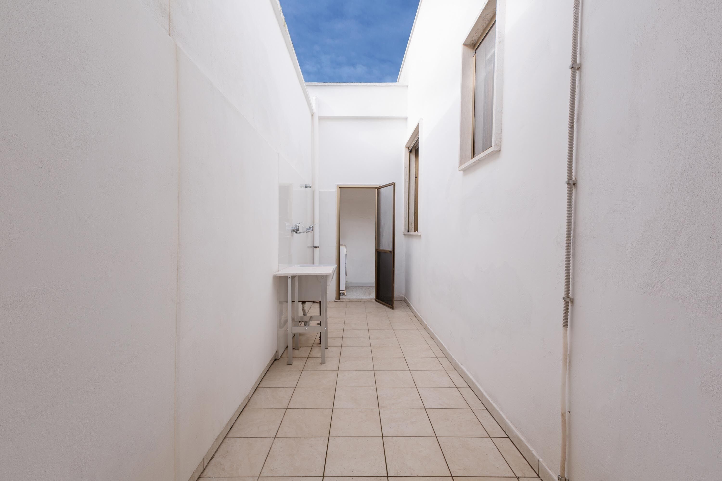 A narrow hallway with a skylight, a white sink, and a door leading to another room.