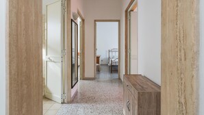 A hallway with a wooden cabinet, a bed with a metal frame, and a door leading to another room. - 3702 La Spiaggetta - Padula Fede by Barbarhouse (Porto Cesareo)