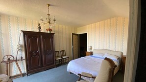 Un dormitorio con una cama grande, un armario de madera, un candelabro y una silla.
