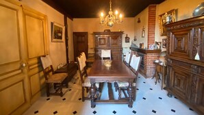 Un comedor con una larga mesa de madera, sillas, un candelabro y una chimenea.
