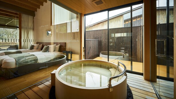 A modern bedroom with a large bed, a separate sitting area, and a glass-enclosed jacuzzi. - Sanso Amanosato (Katsuragi)