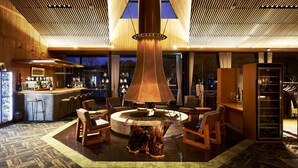 A modern bar area with a central wooden table, bar stools, and a large hanging light fixture. - Sanso Amanosato (Katsuragi)