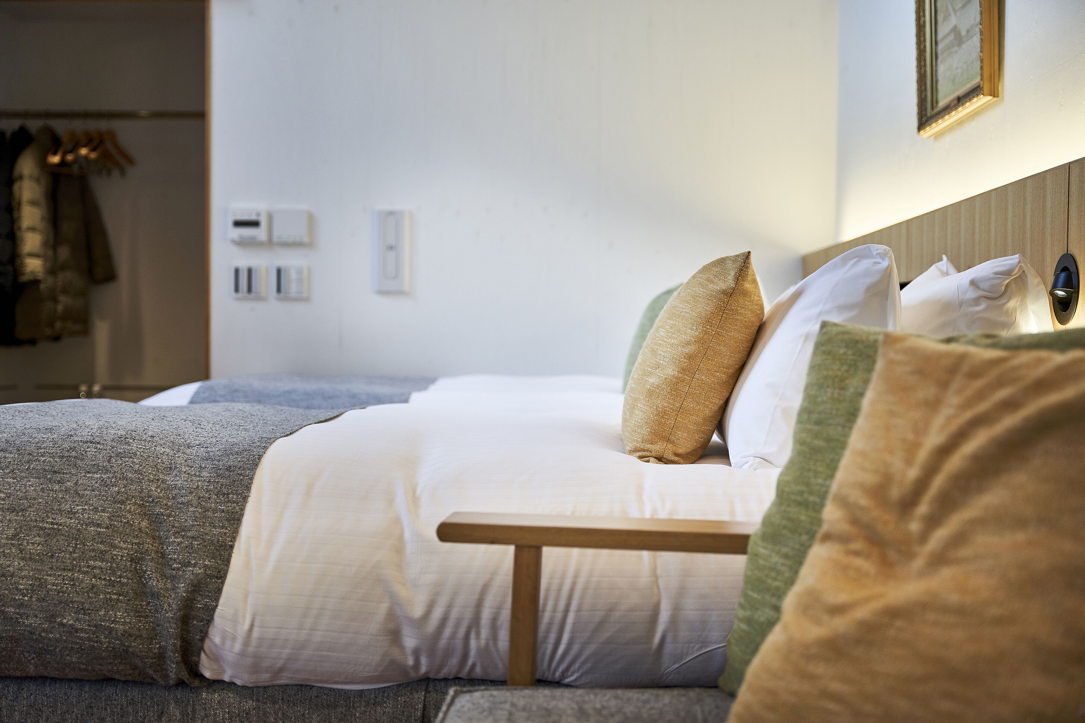 A neatly made bed with a wooden headboard, a bedside table, and a wall-mounted light fixture.