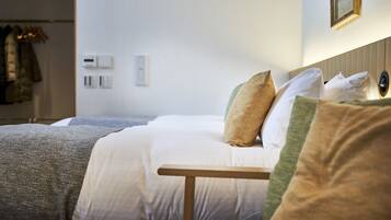 A neatly made bed with a wooden headboard, a bedside table, and a wall-mounted light fixture.