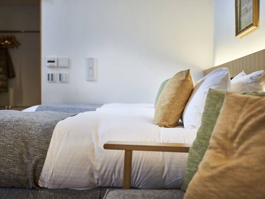 A neatly made bed with a wooden headboard, a bedside table, and a wall-mounted light fixture.