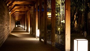 A corridor with wooden beams and brick walls, leading to a bright exit. - Sanso Amanosato (Katsuragi)