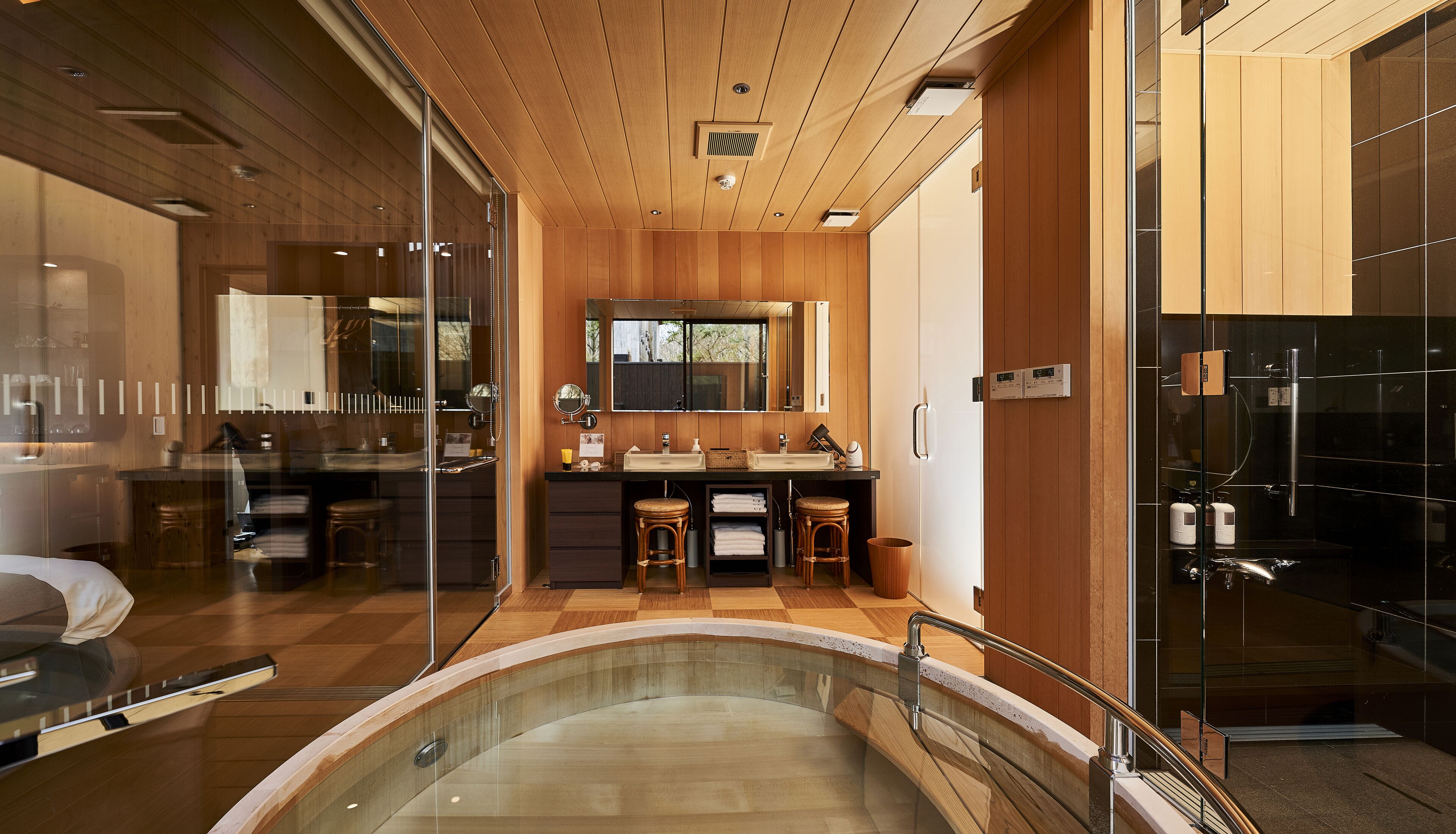 Een moderne badkamer met een douchecabine van glas, houten lambrisering en een grote spiegel boven de wastafel.