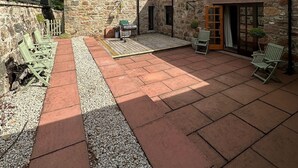 A stone building with a patio area, outdoor seating, and a grill. - Lurg Lodge (Inverurie)
