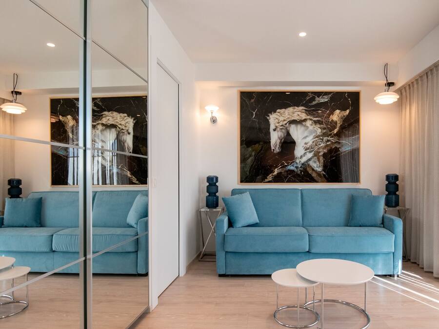 A modern living room with a blue sofa, a white coffee table, and a large abstract painting on the wall.