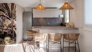 A modern kitchen with a marble backsplash, two pendant lights, and a refrigerator. - Résidence Hôtelière Chambord (Menton)