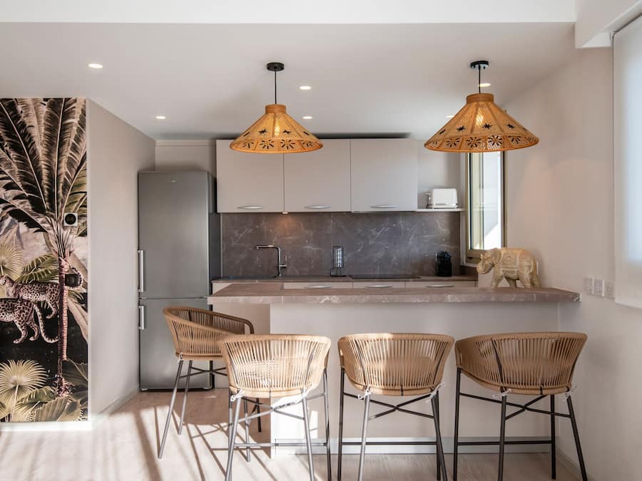 Una cocina moderna con salpicadero de mármol, dos lámparas colgantes y un refrigerador.