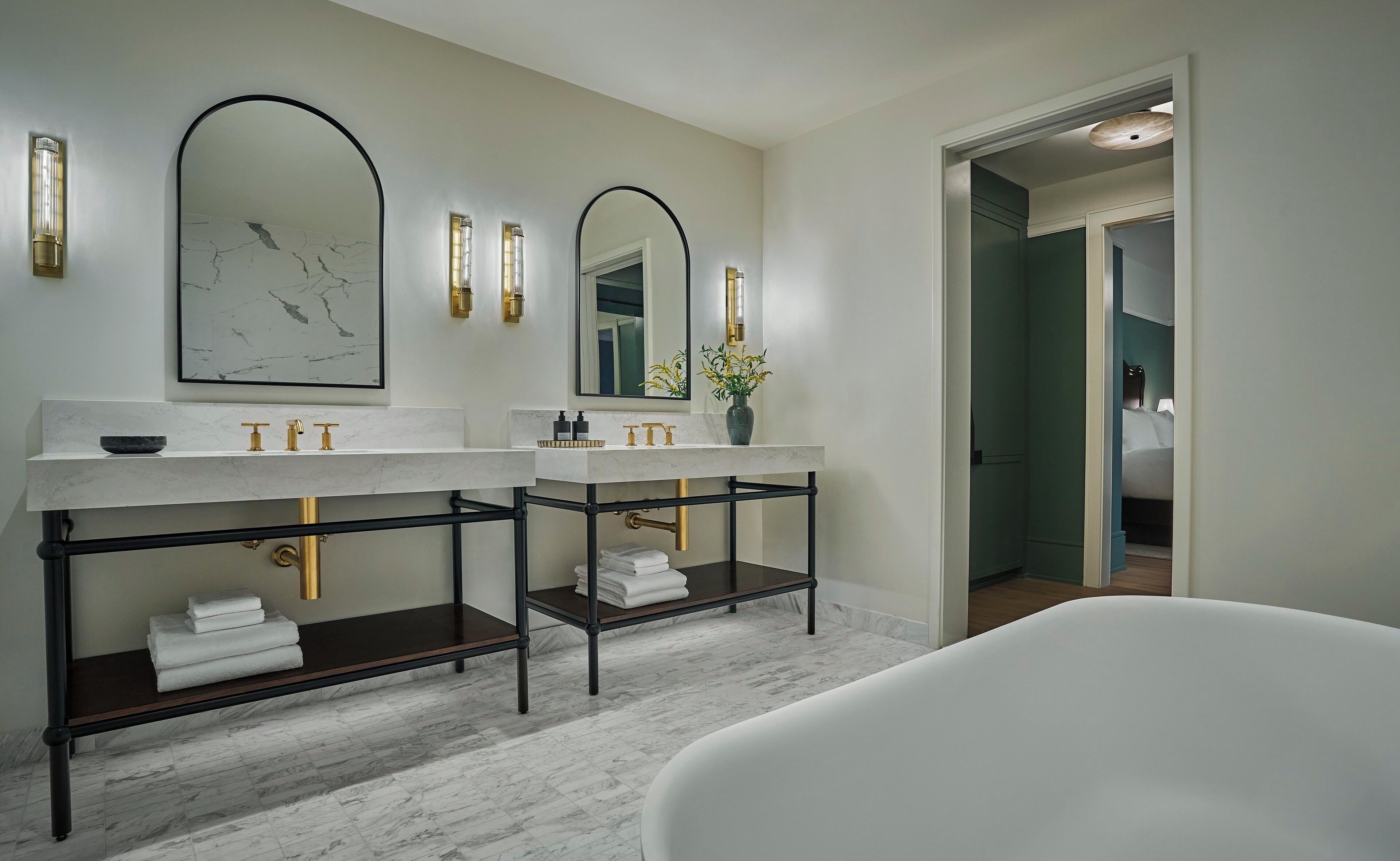 A modern bathroom with two sinks, a large mirror, and a bathtub.