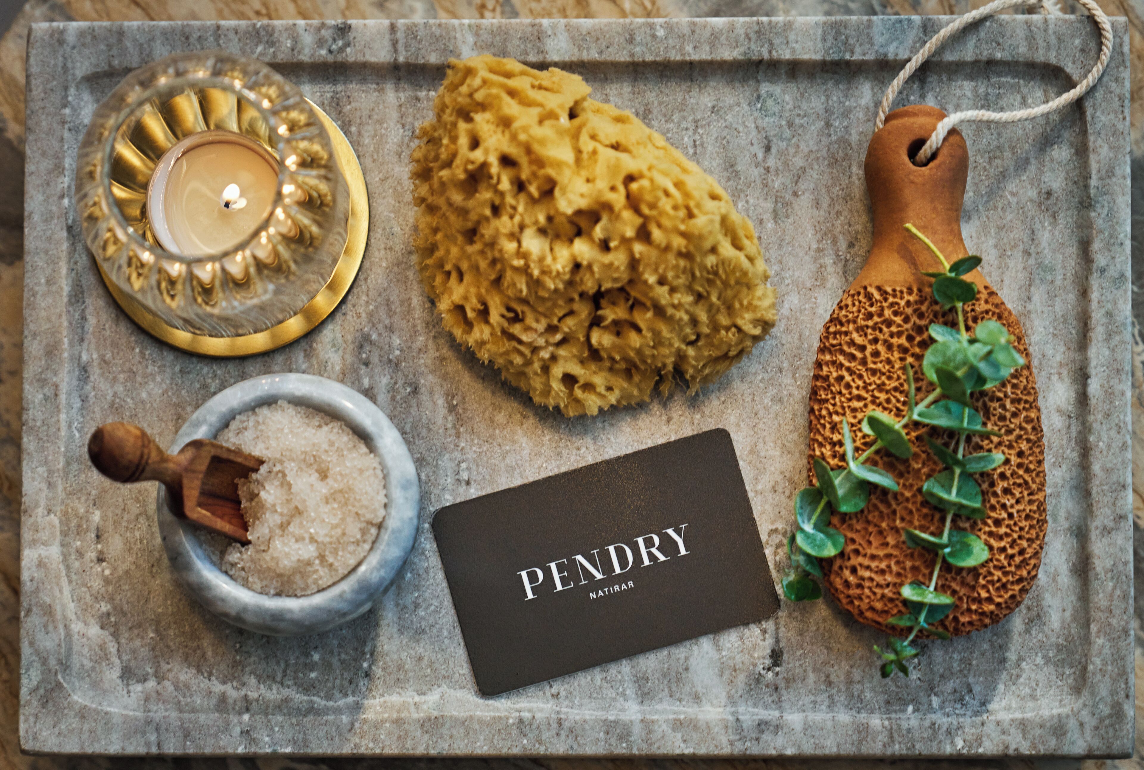 A tray with a candle, a sponge, a wooden scoop, and a card labeled "PENDRY NATIRAR".