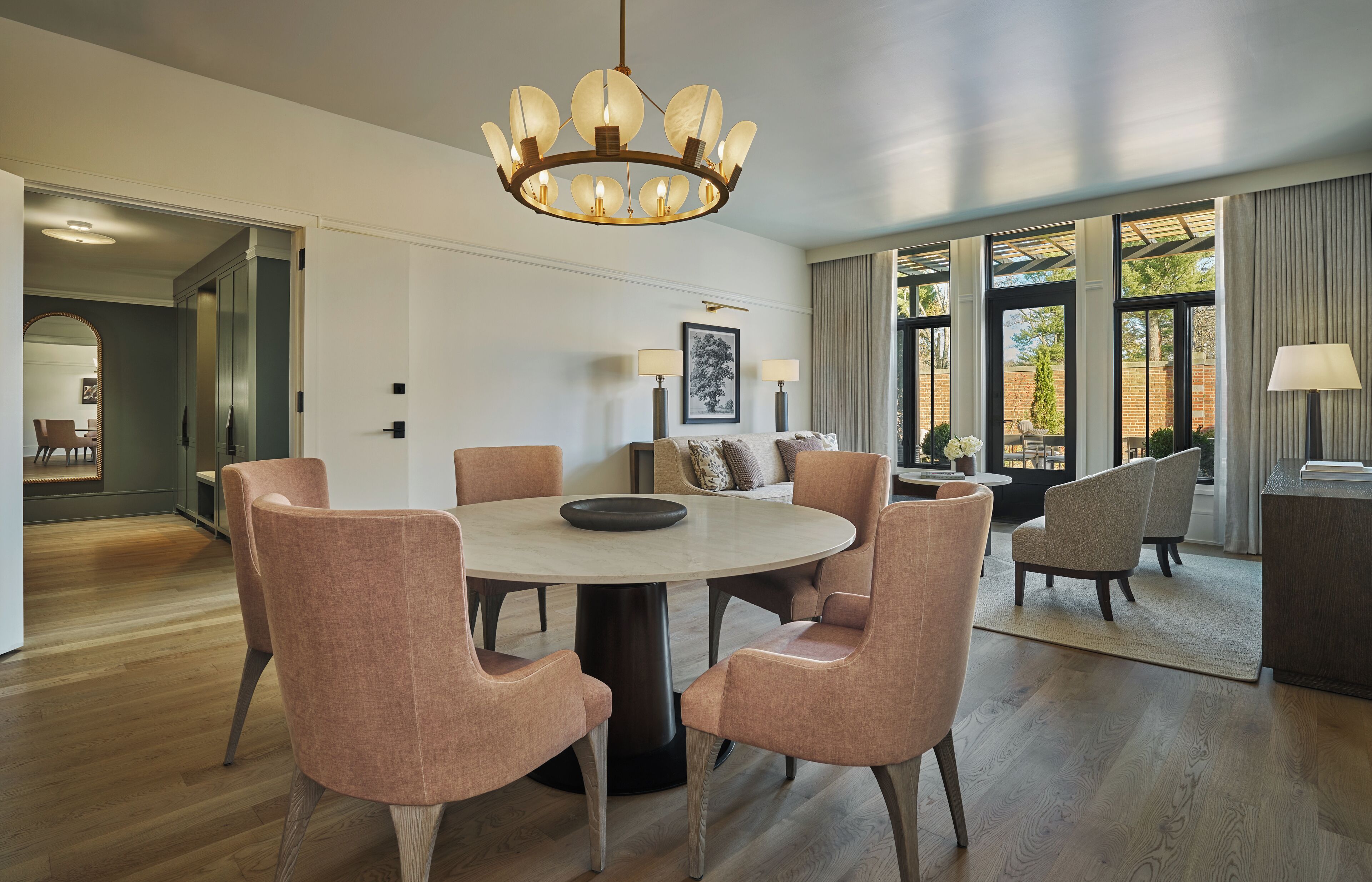 A modern dining area with a round table, six chairs, and a chandelier.