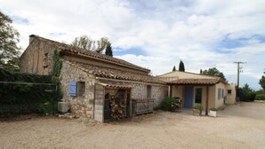 A rustic stone building with a tiled roof, a wooden door, and a small garden area. - Maison Aix en Provence (Aix-en-Provence)