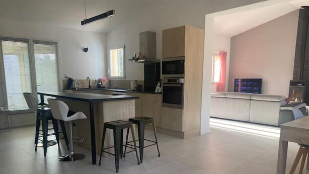A modern kitchen with a central island, bar stools, and a dining area with a table and chairs. - Maison Aix en Provence (Aix-en-Provence)