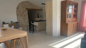 A dining area with a wooden table and chairs, a stone archway, and a kitchen in the background. - Maison Aix en Provence (Aix-en-Provence)