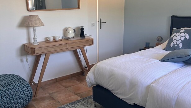 A bedroom with a bed, bedside table, lamp, and a hanging light fixture. - Les Petites Terrasses (Grasse)