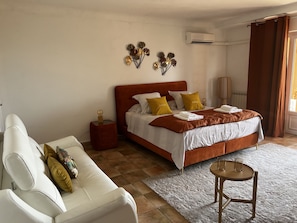 A bedroom with a bed, bedside table, nightstand, and a small round table. - Les Petites Terrasses (Grasse)