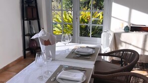 A dining table set for four with a view of greenery through a glass door. - Les Petites Terrasses (Grasse)