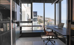 A modern office space with a large window, a desk with a laptop, and a bookshelf. - Aurum 501 (Cape Town)