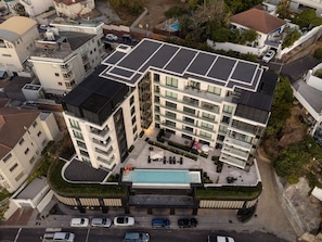 A modern multi-story hotel with a rooftop pool, a covered outdoor area, and a parking lot. - Aurum 501 (Cape Town)