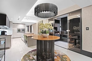 A modern kitchen with white cabinetry, a central island, and a dining area with a round table and chairs. - Aurum 501 (Cape Town)
