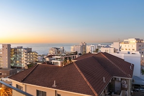 A coastal cityscape with a prominent building featuring a tiled roof and multiple balconies. - Aurum 501 (Cape Town)
