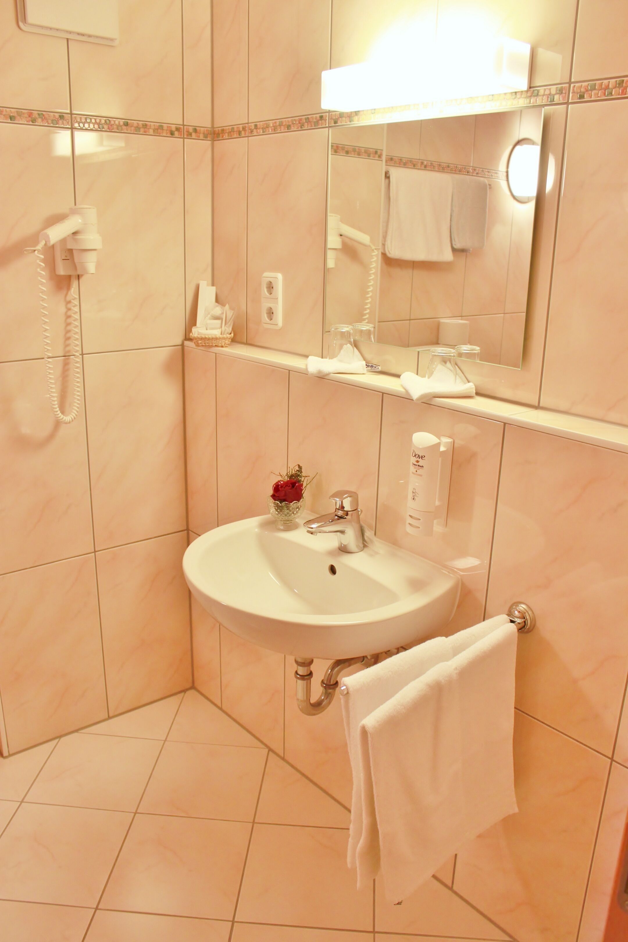 Ein Badezimmer mit Waschbecken, Spiegel, Handtuchhalter und Telefon.