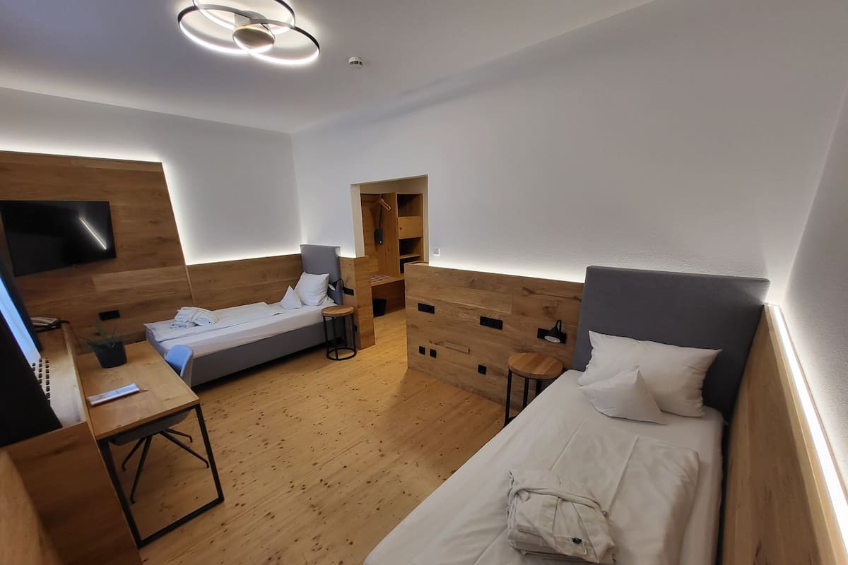 Une chambre d’hôtel moderne équipée de deux lits, d’un bureau, d’une télévision et d’un panneau mural en bois.