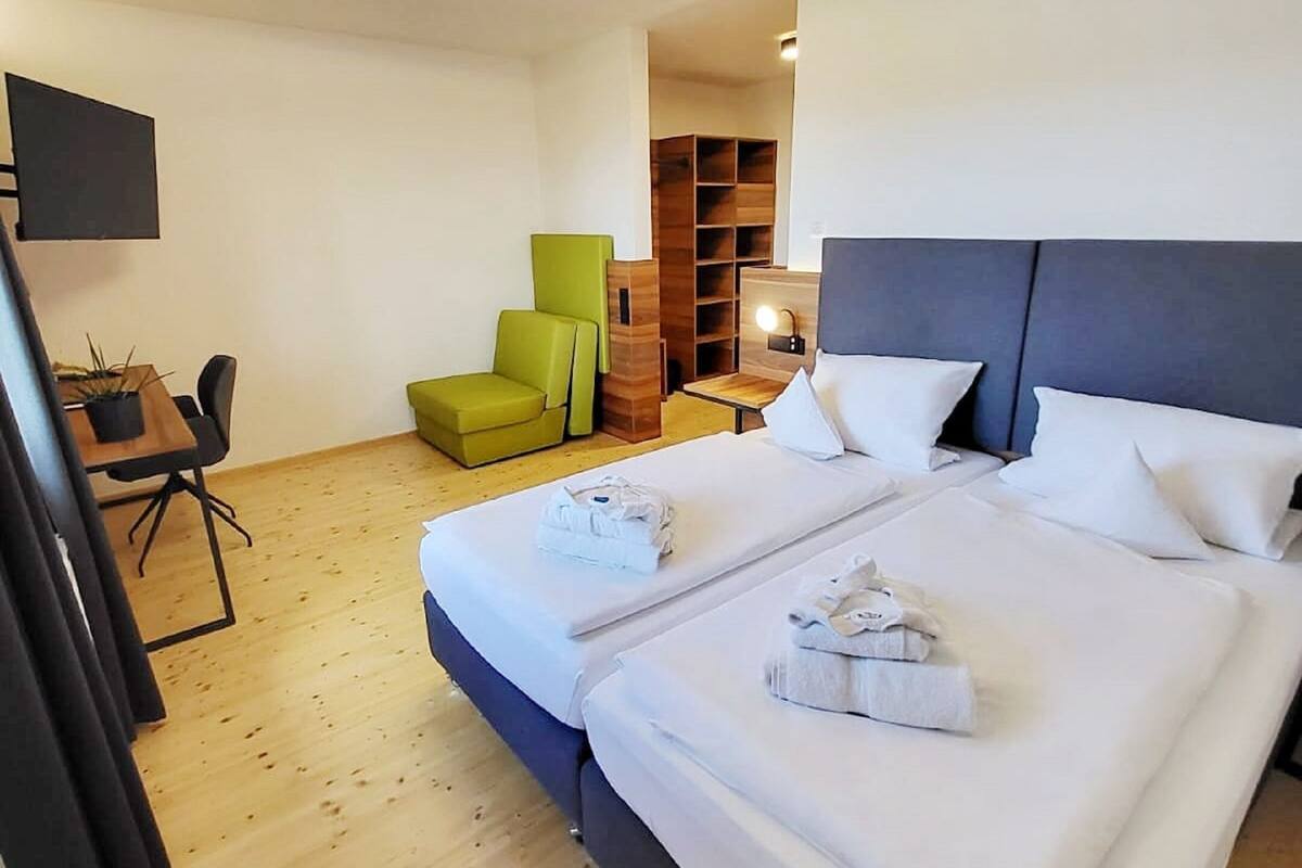 Une chambre d’hôtel avec deux lits, un bureau, une chaise et un téléviseur.