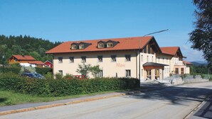 Ein Gebäude mit rotem Ziegeldach, zahlreichen Fenstern und einem Schild mit der Aufschrift 'Wirtshaus'.