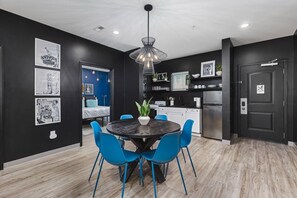 A modern kitchen with black cabinets, a stainless steel refrigerator, and a blue dining area with a round table and chairs. - Condo Near Downtown - WALK to restaurants, bars & music (Nashville)