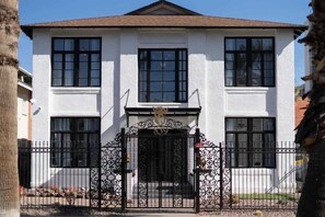 A two-story building with a symmetrical facade, a central entrance with a decorative gate, and a number '839' above the door.