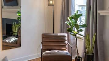 A modern living room with a leather chair, a floor lamp, and potted plants.