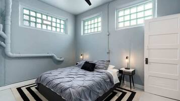 A bedroom with a bed, bedside tables, a ceiling fan, and windows.