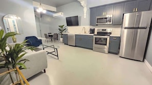 A modern kitchen with grey cabinets, stainless steel appliances, and a dining area with a blue chair and table. - Modern Apartment in the Heart of Phoenix (10) (Phoenix)