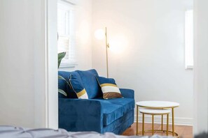 A room with a blue sofa, a small round table, and a floor lamp. - Historic Roosevelt Row Apt Near Dining & (Phoenix)