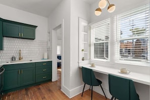 A kitchen with green cabinets, a white countertop, and a window with blinds. - Historic Roosevelt Row Apt Near Dining & (Phoenix)