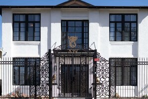 Un bâtiment blanc avec un portail en fer forgé noir et le numéro « 839 » au-dessus.